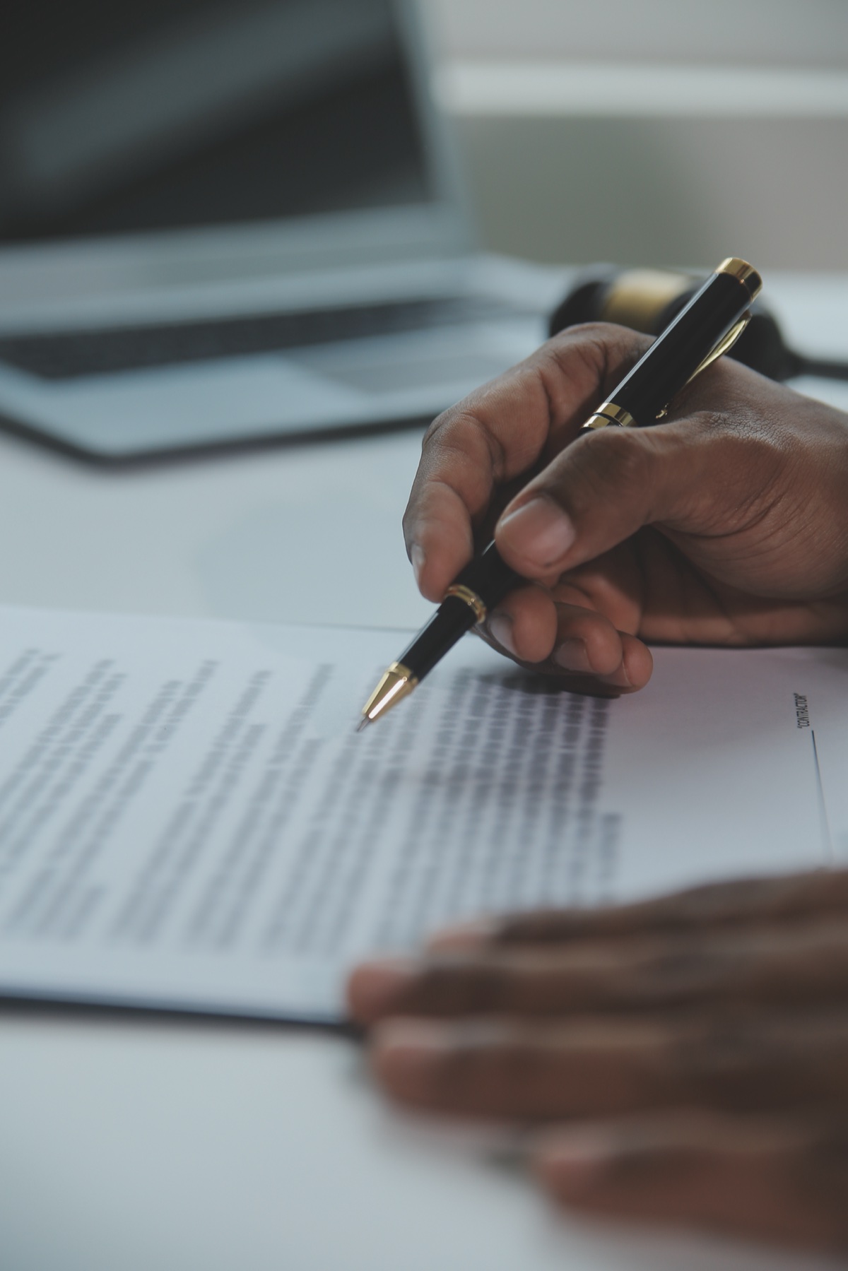 A hand holding a pen over legal documents